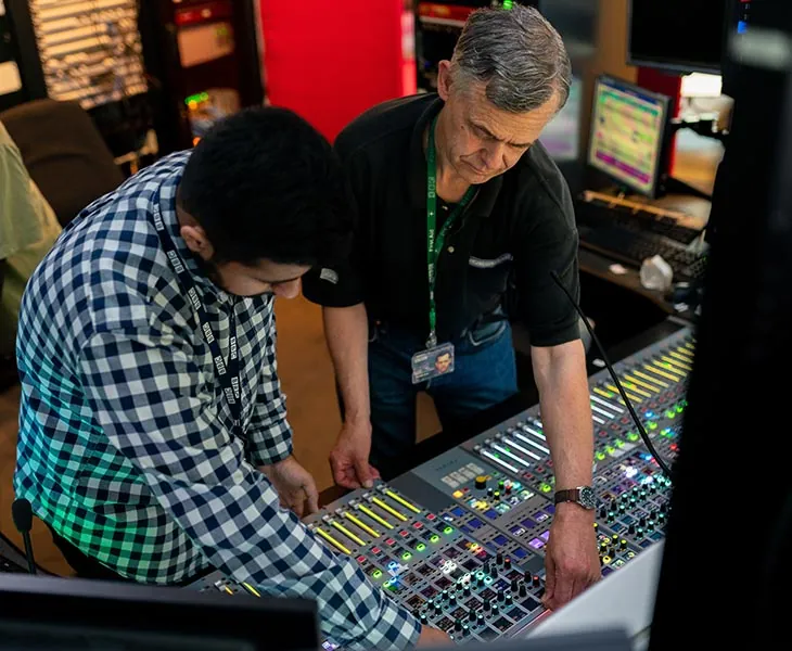Engineers setting up an audio mixing console