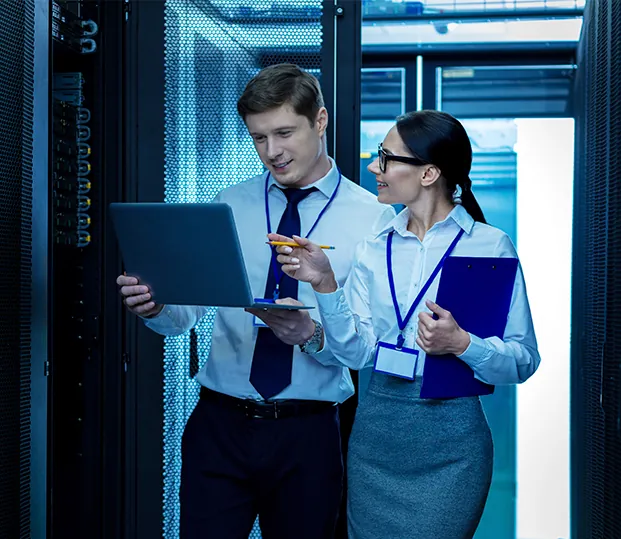 Two engineers reviewing a laptop in a server room