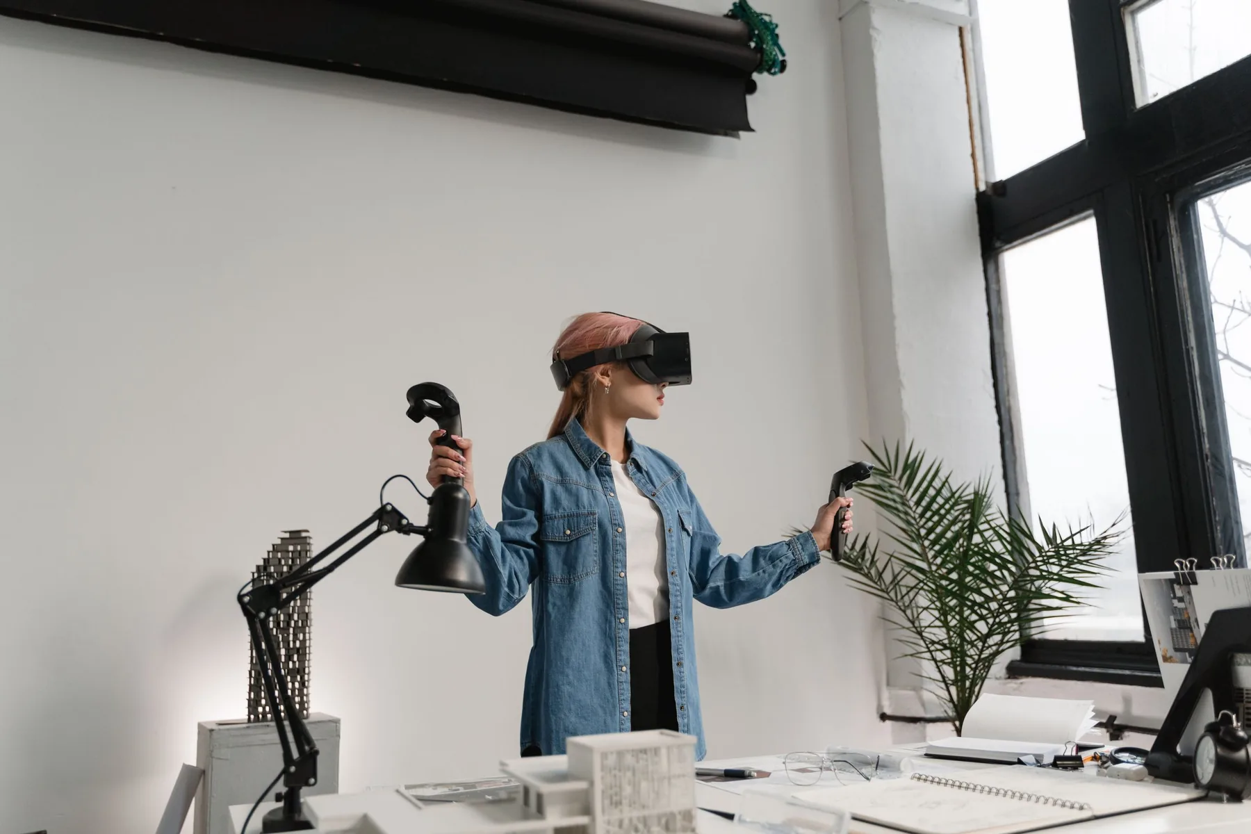 A person using a virtual reality headset and controllers in a bright studio